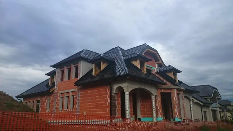 Velika opečna hiša s temno streho in več frčadami